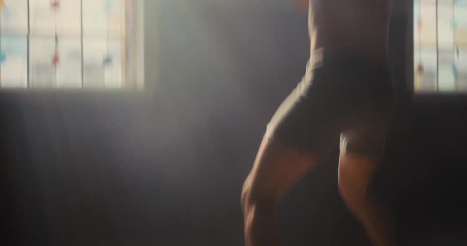 Man shadowboxes while in a room with colorful windows during the daytime