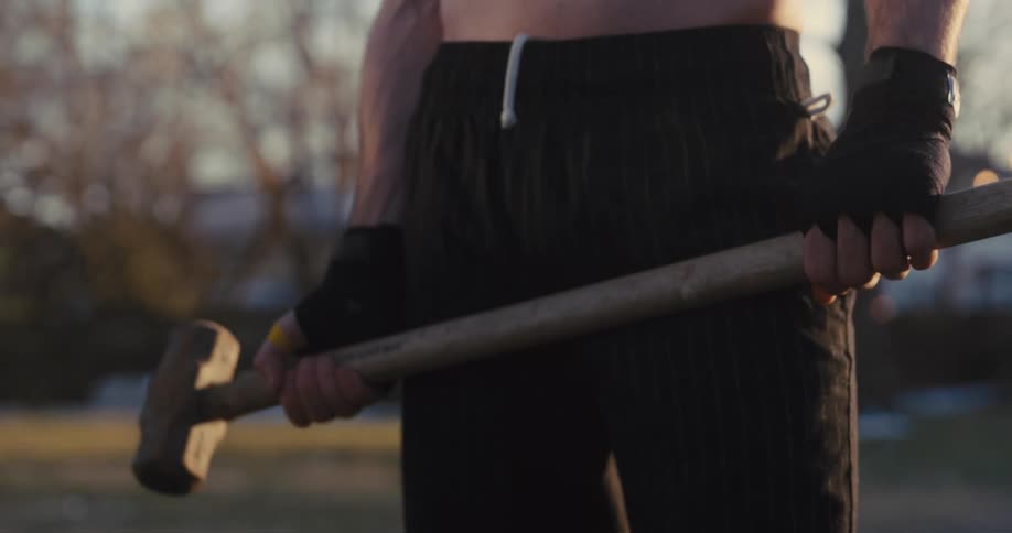 A man standing outdoors with a sledge hammer