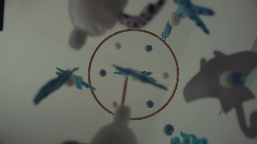 Hand reaches for bird mobile hanging in nursery