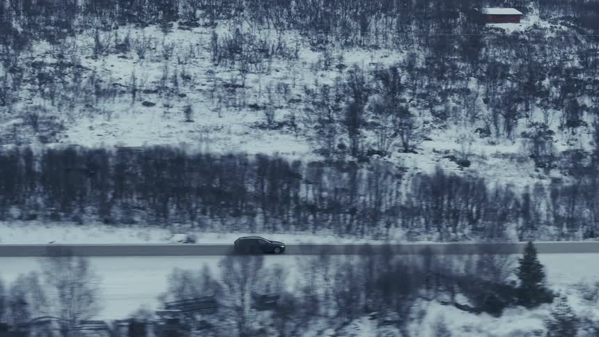 Car driving along a road through a snowcovered landscape seen from above