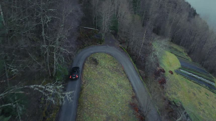 An aerial view of a car driving on a windy road