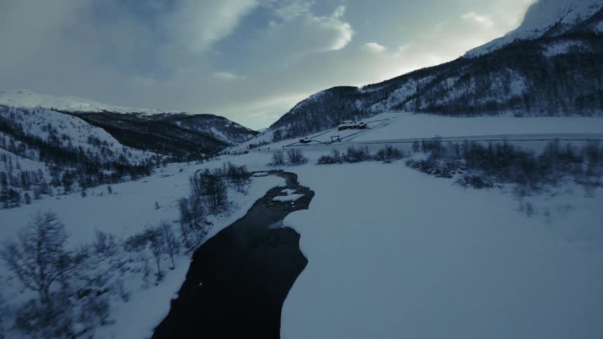 Moving over a stream in the snow covered forested mountain valley