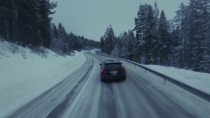 Car traveling on a snow covered forested mountain road