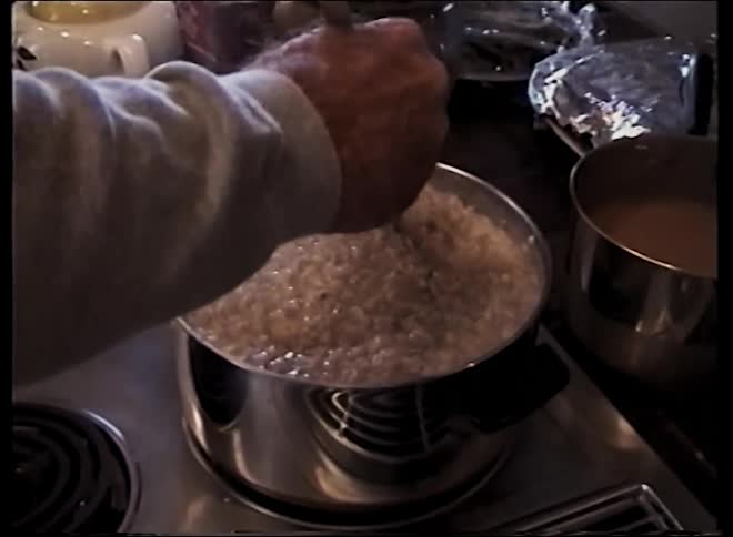 A chef cooking on the stove stirring and turning the food in a pot with a spoon