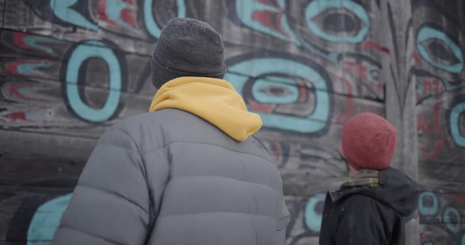 Two people looking at a wall outdoors
