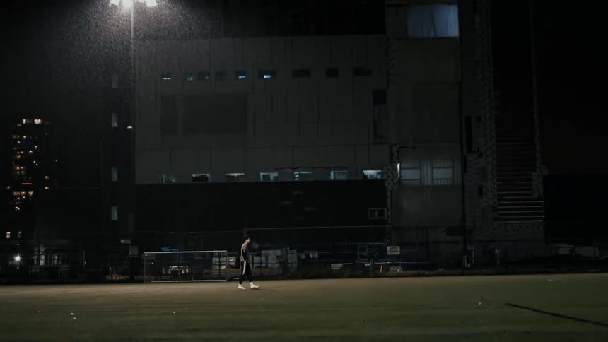Lone silhouette on nighttime field lit by artificial light