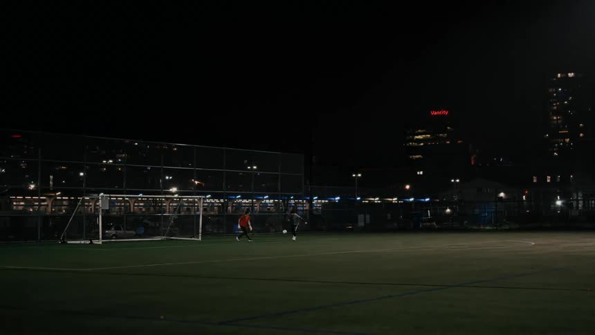 Soccer players on the field as lights from buildings glow in the distance
