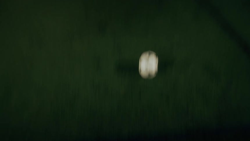 Person performing skills on a grassy field at night with a soccer ball
