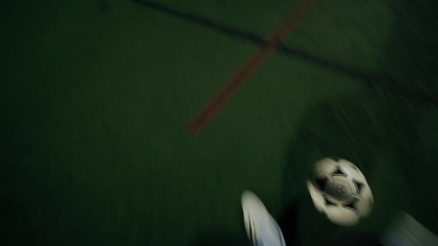 A person kicking a soccer ball at a goal