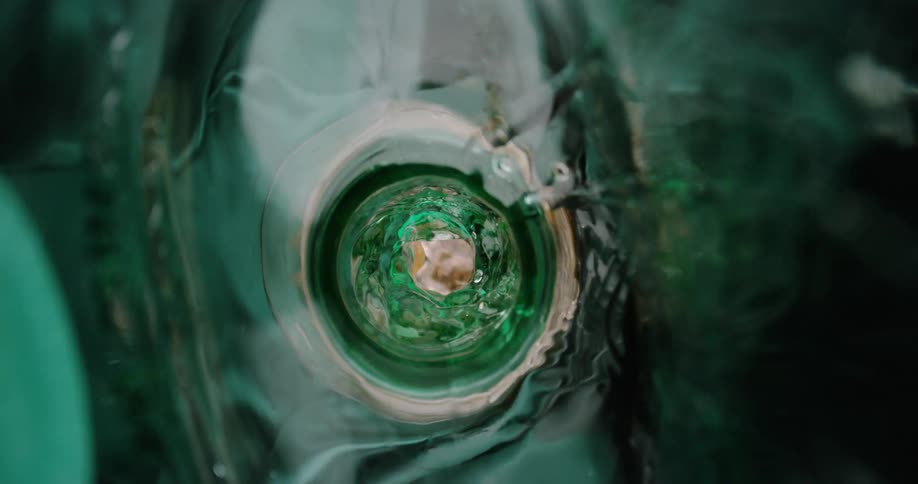 Interior view of a green bottle neck with liquid in motion