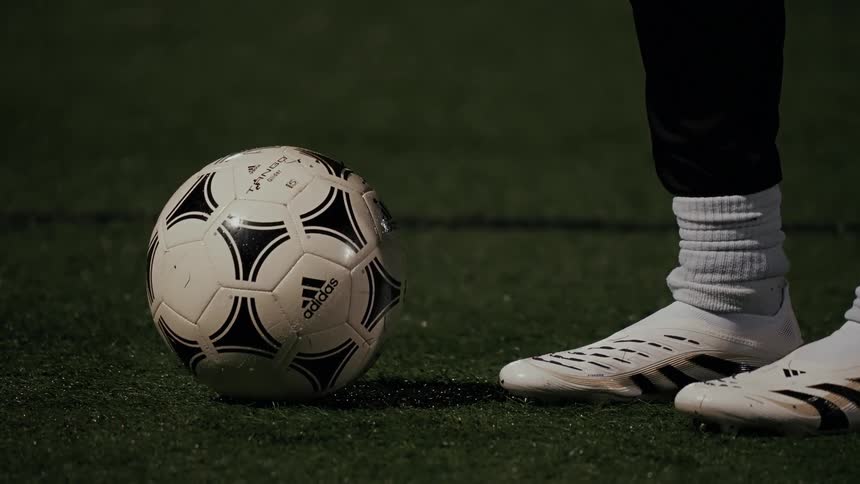 Soccer ball next to a white cleat on a grassy field
