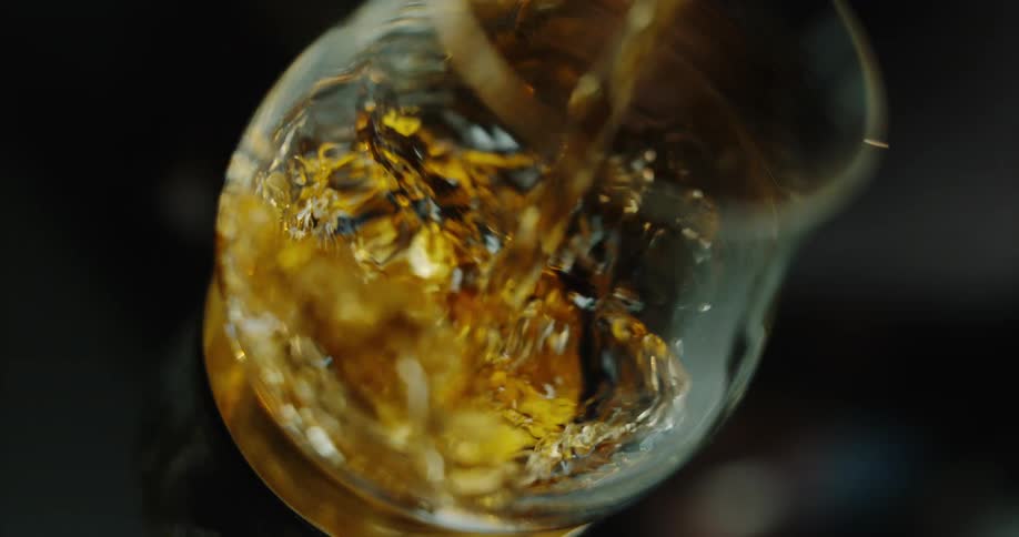 Amber liquid being poured into a crystal glass