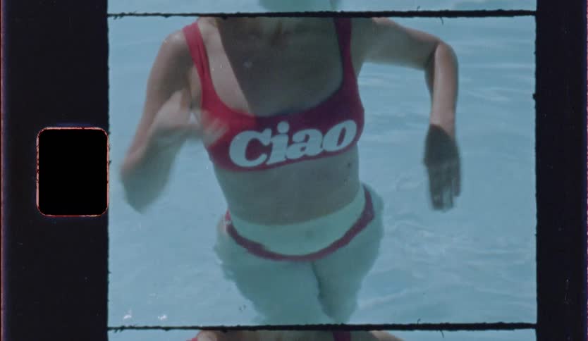 Person wears a red bikini with the word ciao and stands in shallow water