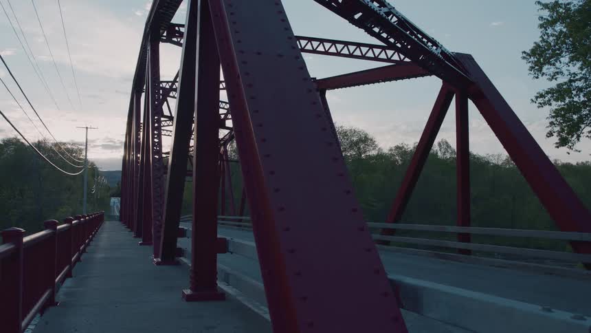 Red metal bridge structure seen from the side at dusk