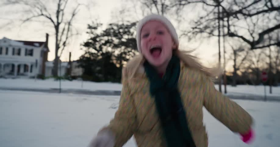 Girl running through the snow in the front yards of a neighborhood