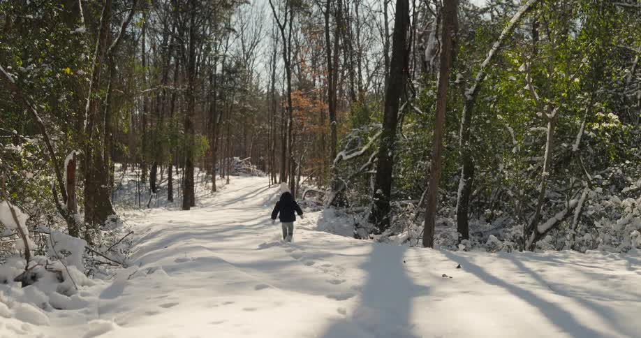 A child running in the snow in a forest