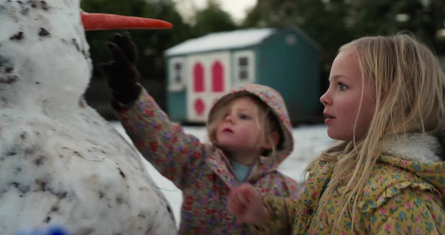 Two children building a snowman outdoors