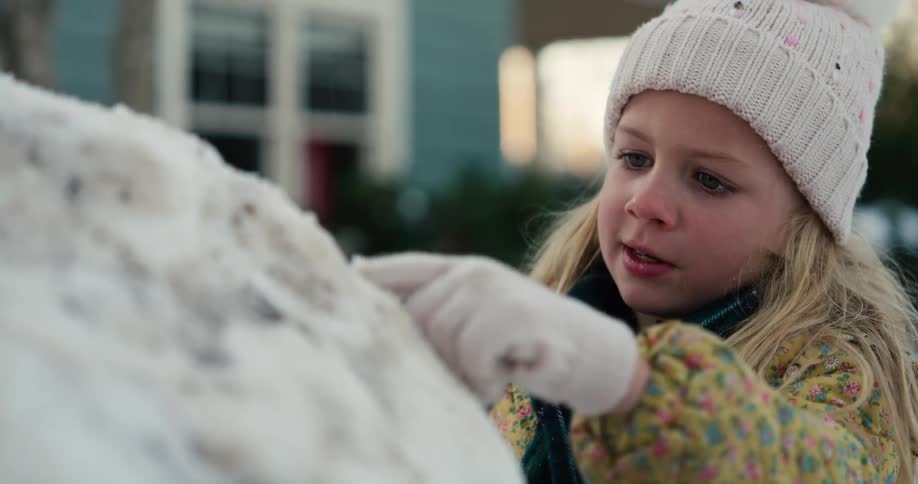 Girl making a snowman in her front yard