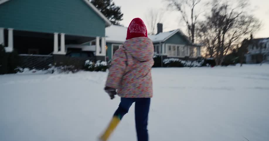 Three young girls run together across the snow covered ground in their neighborhood