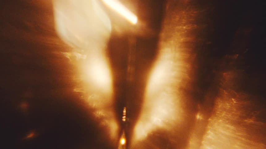 Golden light beams radiating between abstract shapes against a dark background