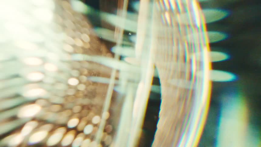 Golden light refracting through textured glass creating a swirling abstract pattern of bokeh and prism flares
