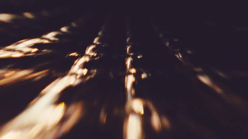 Abstract golden light trails streak across a dark reflective surface