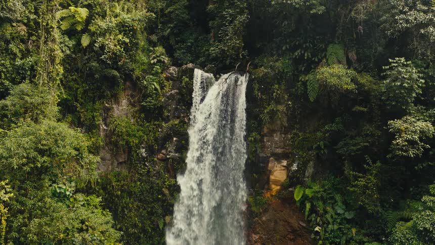 Waterfall flowing between rocks and dense vegetation in a tropical forest