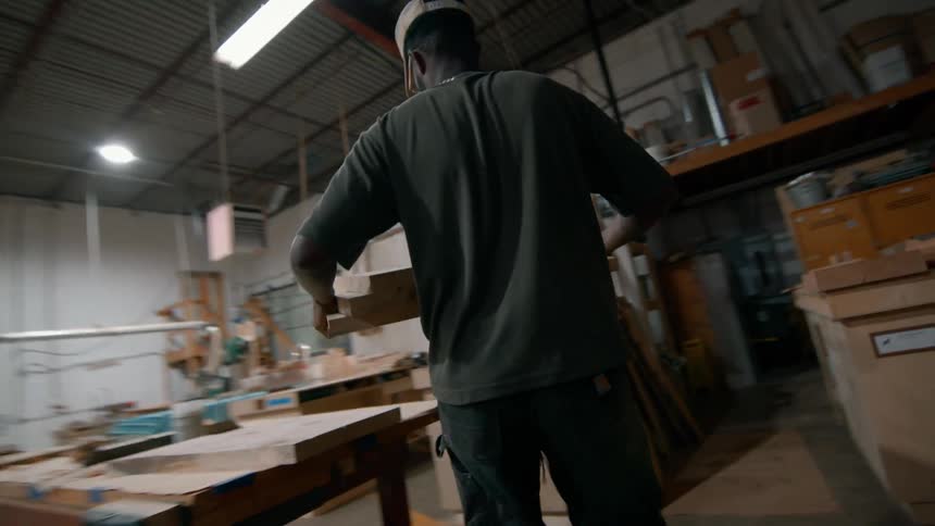 Man carries pieces of wood while working in a workshop
