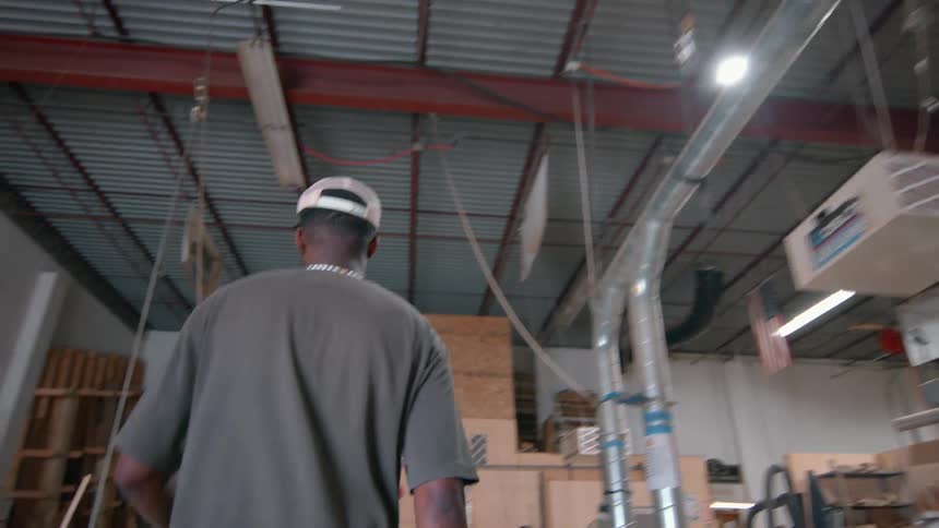 Man wearing a cap walking inside an industrial workshop