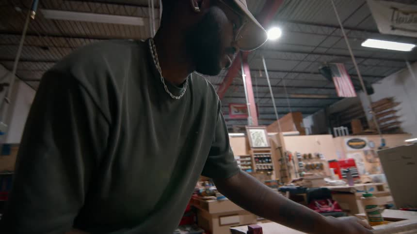 Man working with wood and clamps on a table in a workshop