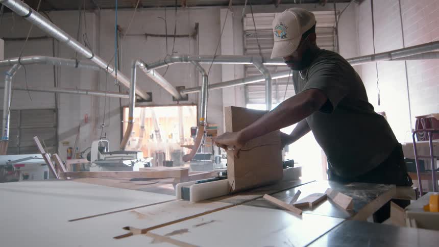 Man cutting wood with table saw in carpentry workshop