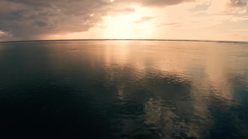 Sun sets on the horizon reflecting over calm ocean surface