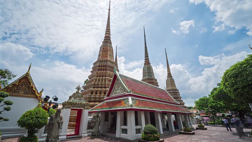 Temple with ornate spires and red roof under partly cloudy sky