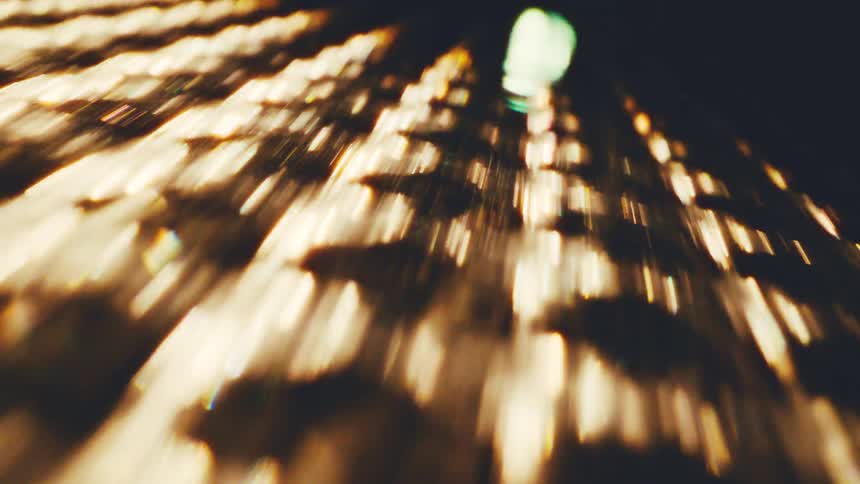 A blurred highangle view of city lights at night creating a streaking bokeh effect that suggests rapid movement the golden and white lights shimmer against a dark background evoking the feeling of a fastpaced urban environment or a timelapse sequen