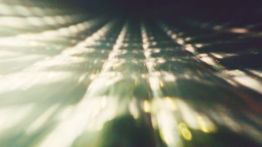Blurred light lines forming geometric pattern in light and greenish tones