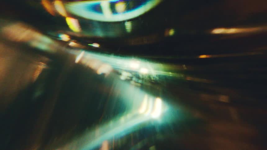Distorted light reflections on curved surface with green and golden tones