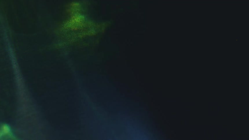 Vibrant light leaks and prismatic refractions shifting across a dark textured surface while tiny dust particles float