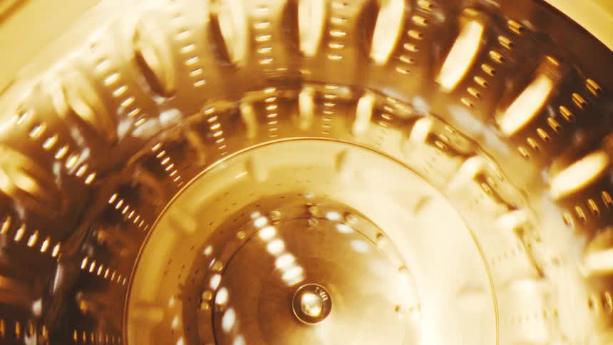 A spinning wheel with several small holes illuminated by a bright golden light