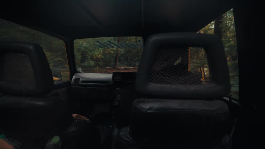 The car jumps around while driving on a dirt trial in the forest