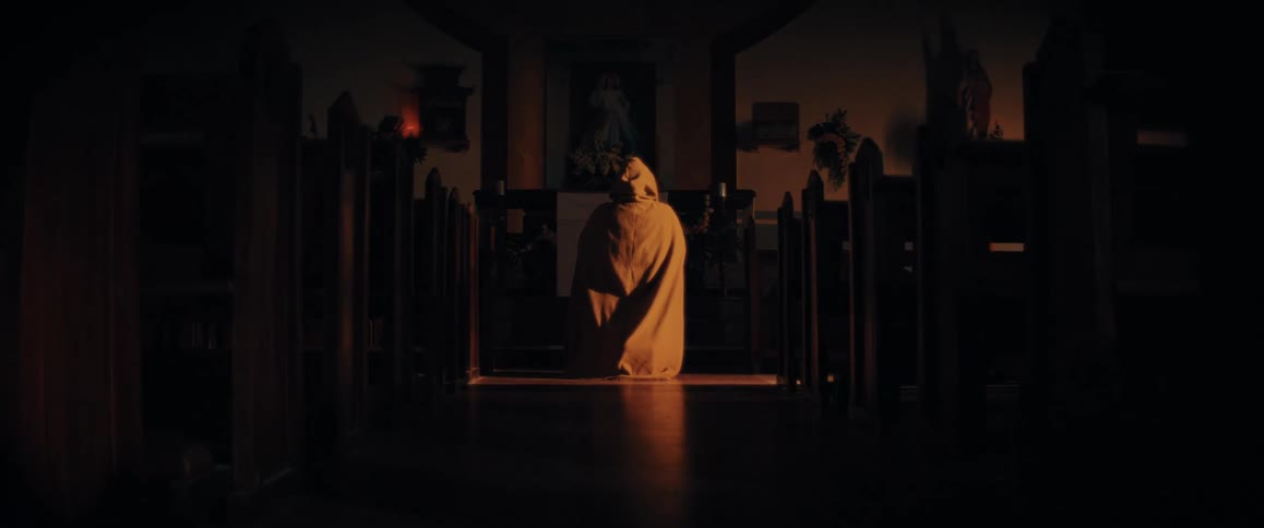 A person in a cloak kneeling in a church