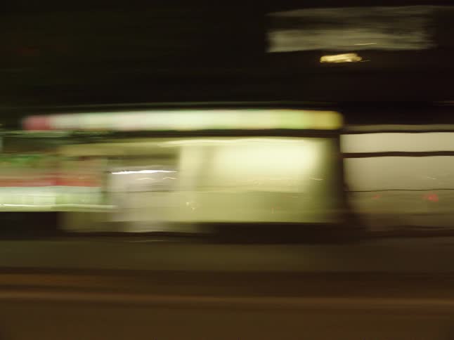 Streets and traffic on an urban area with many stores and buildings outdoors during night time