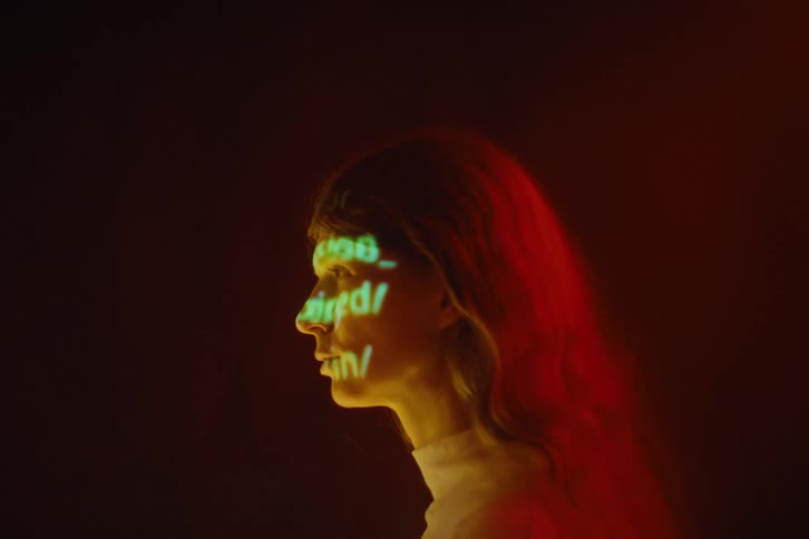 A side profile view shows green text including words like memory overflow and session expired projected onto the face and neck of a woman with red hair against a dark background