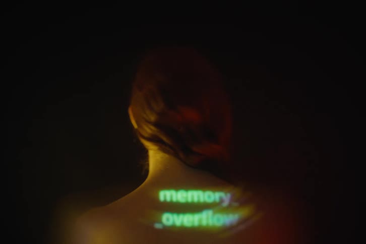 A view from behind shows green text including words like session expired and memory overflow projected onto the back and neck of a woman with red hair against a dark background