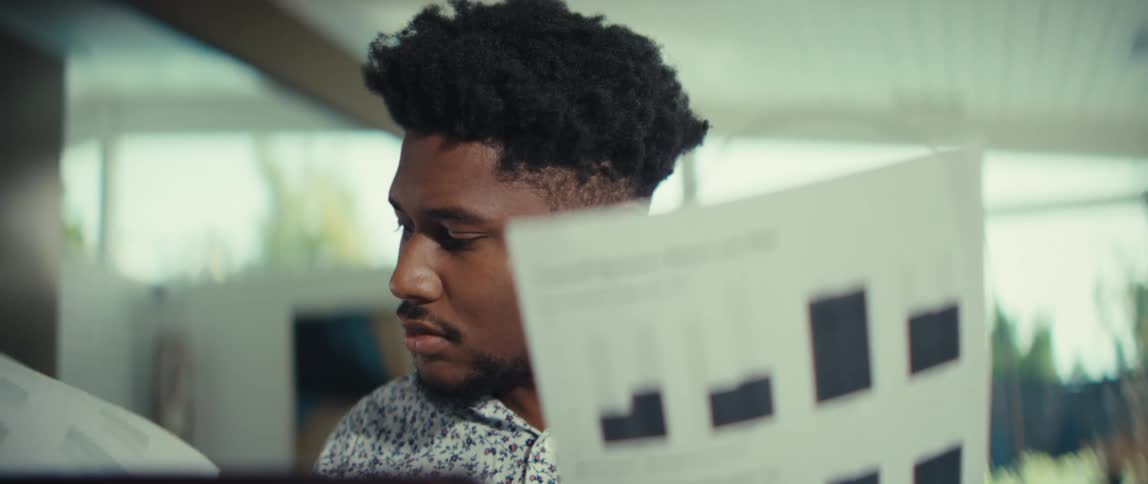 Man holding documents with charts while looking to the side in a bright indoor setting