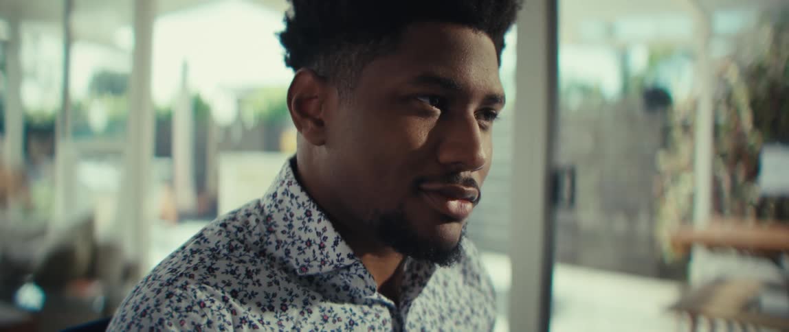 A man in a patterned shirt working with a calculator and financial documentshe transitions from focused data entry to a moment of thoughtful reflection as he looks away from his work