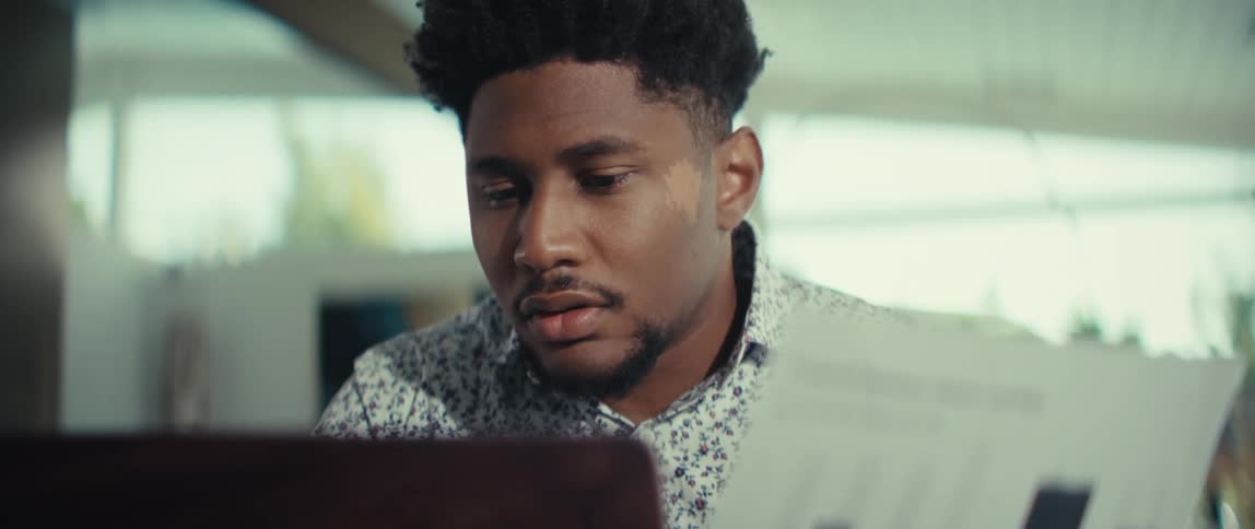 A man looks over a printed chart titled tradeoff between return and risk while sitting behind his laptop