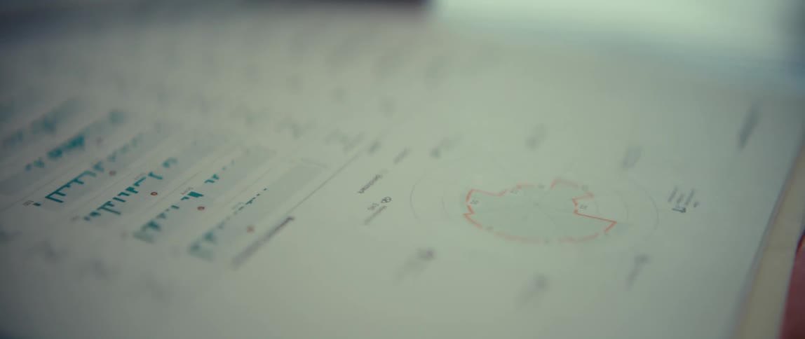 A close view of professional documents featuring blue and green line graphs as well as circular data charts and financial statistics on white paper as the camera moves across the pages