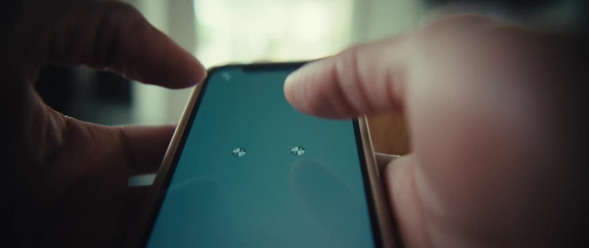 A person uses their thumbs to interact with a smartphone screen containing tracking markers