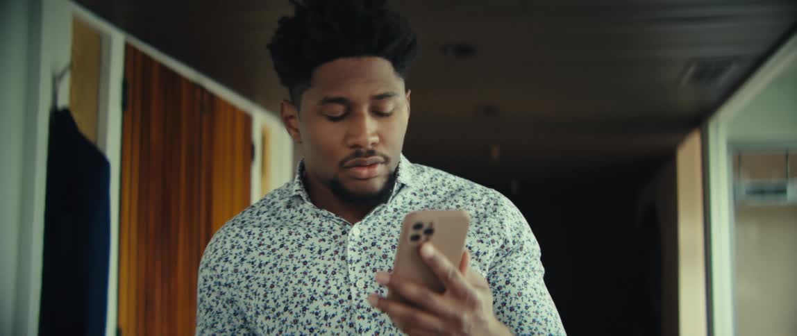 Man walks through a room talking with his phone in his hand