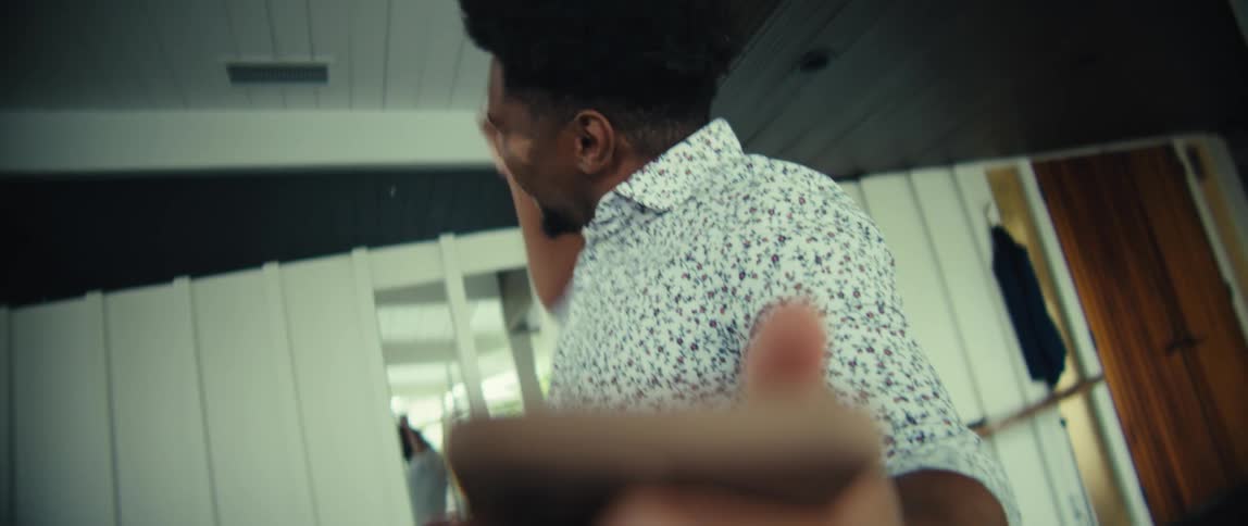 Young adult black man tapping on a smartphone held in his hand then smiling and cheering indoors during day time